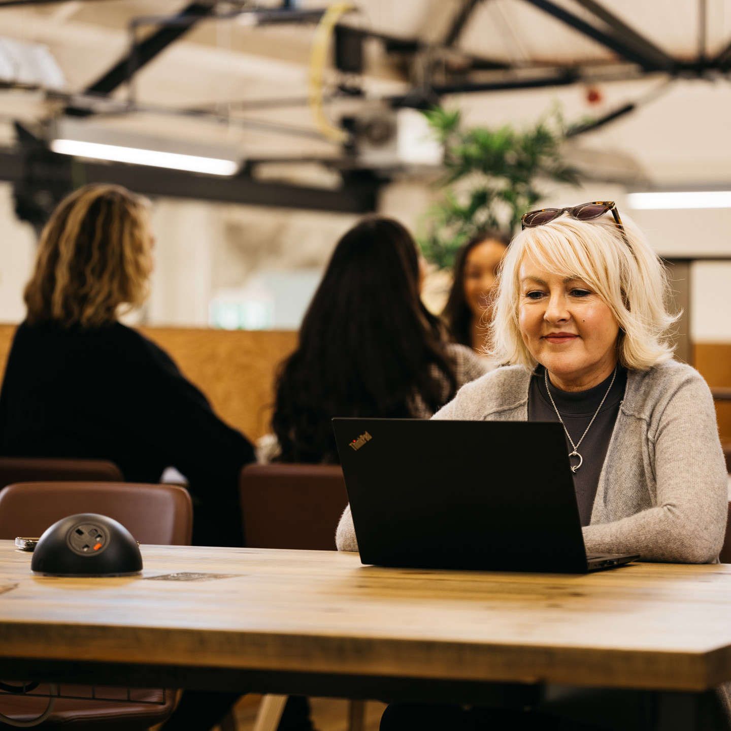 Lady working in IOM Work Cafe mezzanine level with lap top